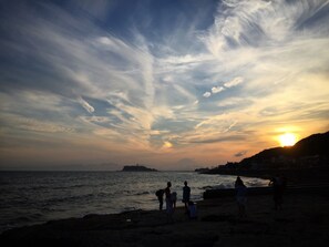 Une scène de plage avec des gens au coucher du soleil.