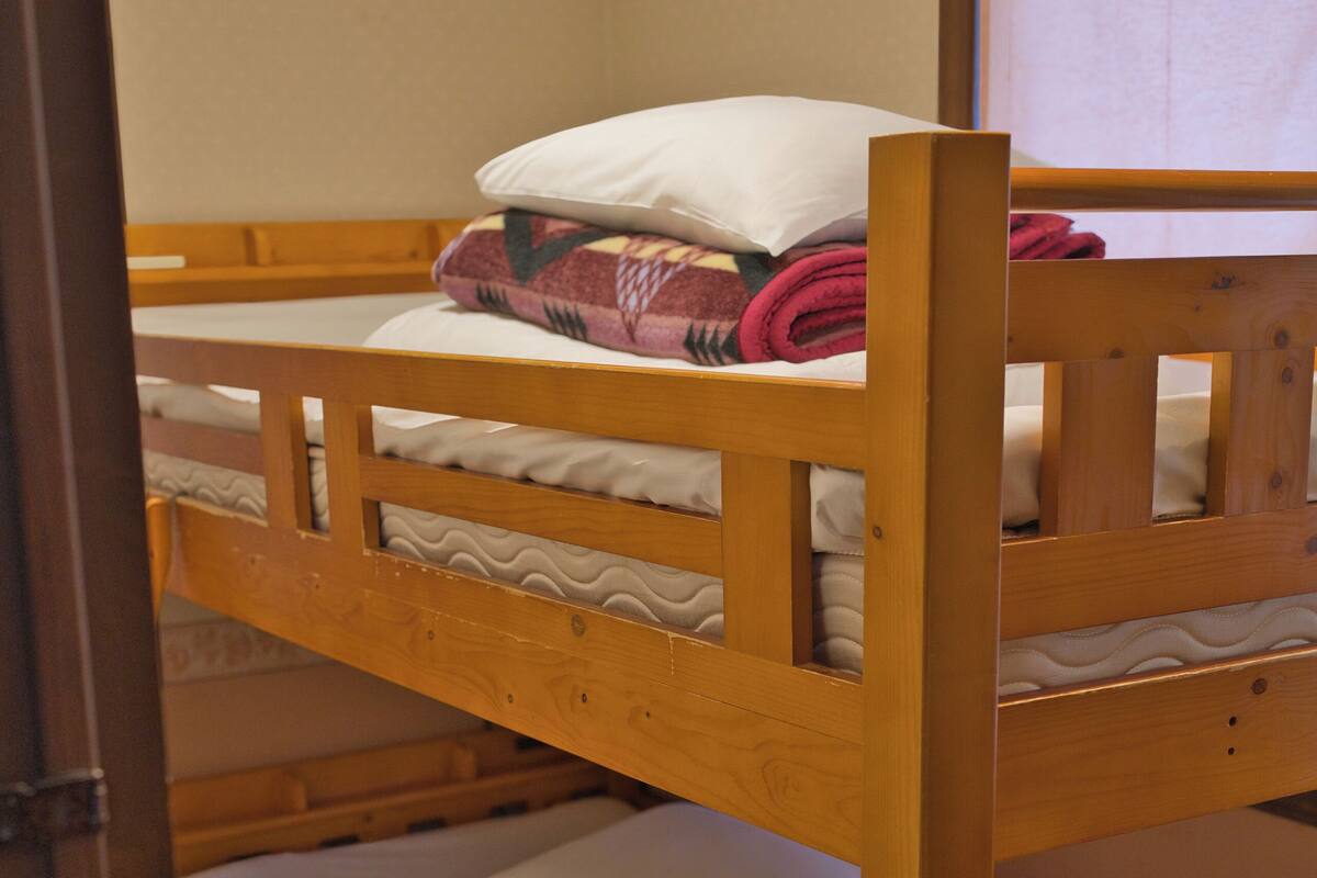 Una litera con ropa de cama blanca y estructura de madera.