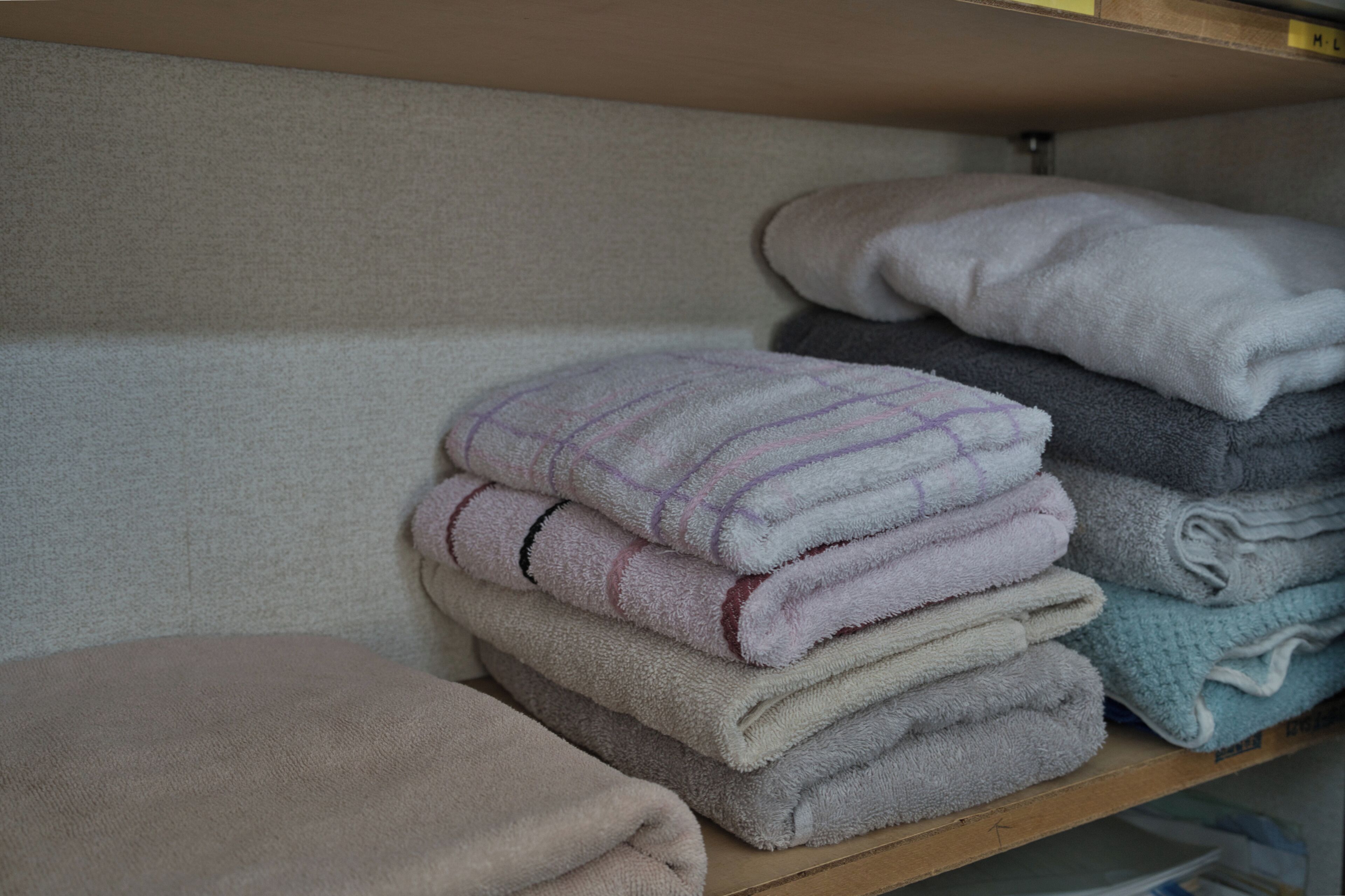 A shelf with folded towels in various colors.