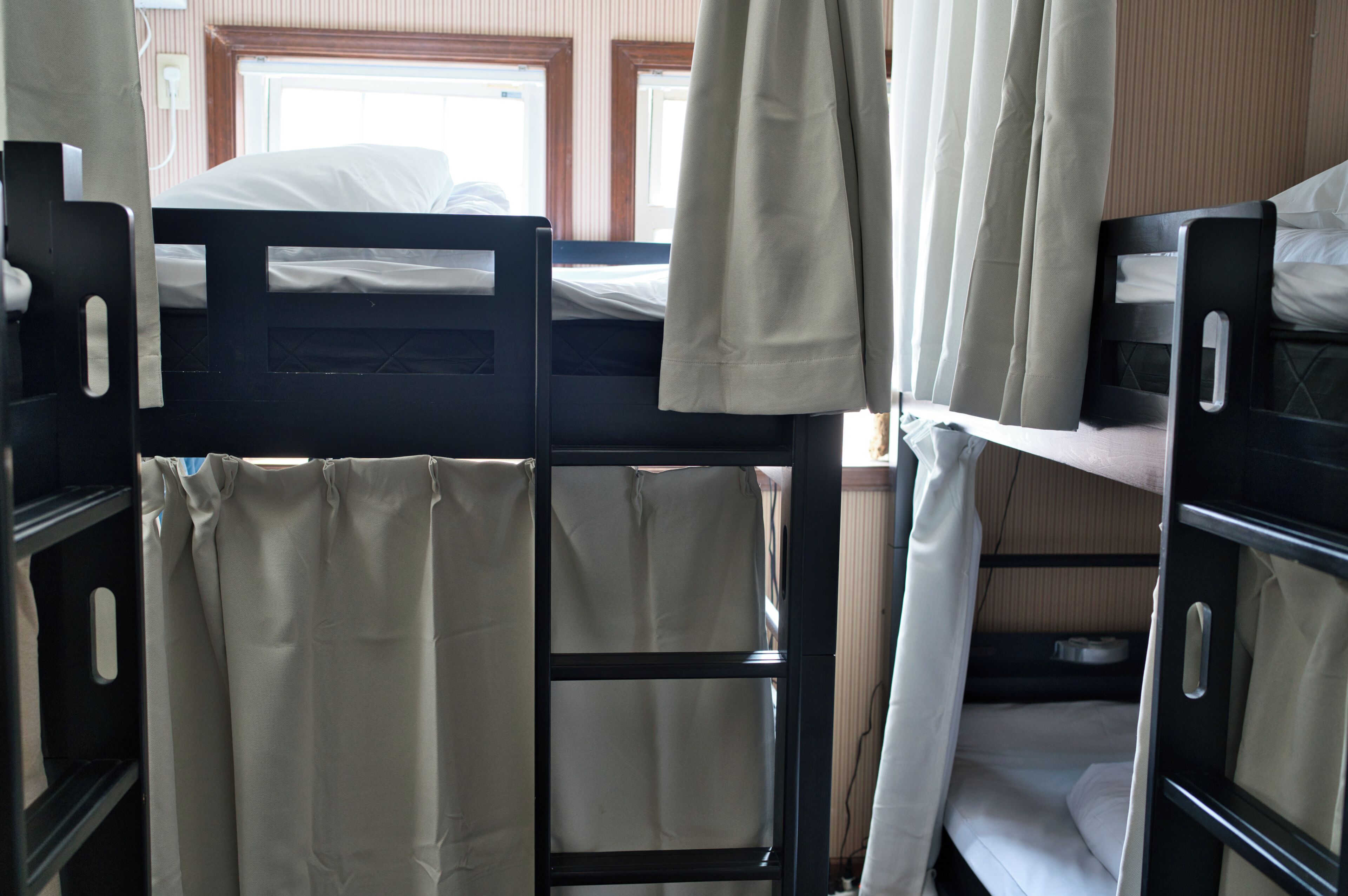 Bunk beds with curtains, a window, and a wooden wall.