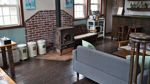 Una habitación acogedora con chimenea de ladrillo, un sofá, una zona de bar con taburetes y un ventanal con obras de arte.