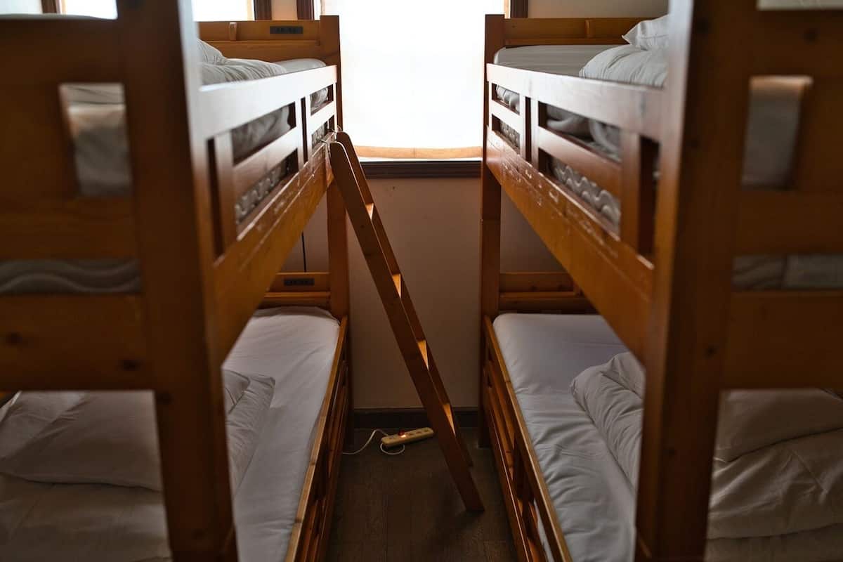 A room with two bunk beds, a ladder, and a window.