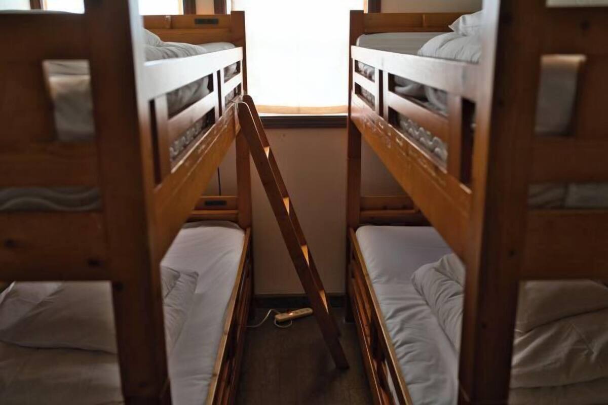 Dormitorio con literas de madera y ropa de cama blanca.