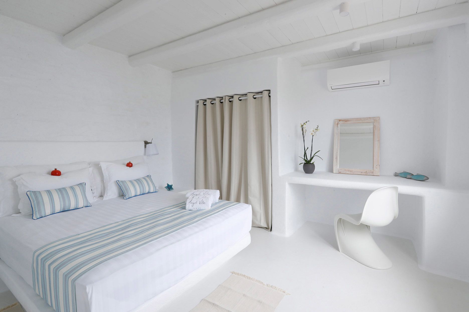 Un dormitorio con una cama, una mesita de noche, una silla, un espejo y una planta en maceta.