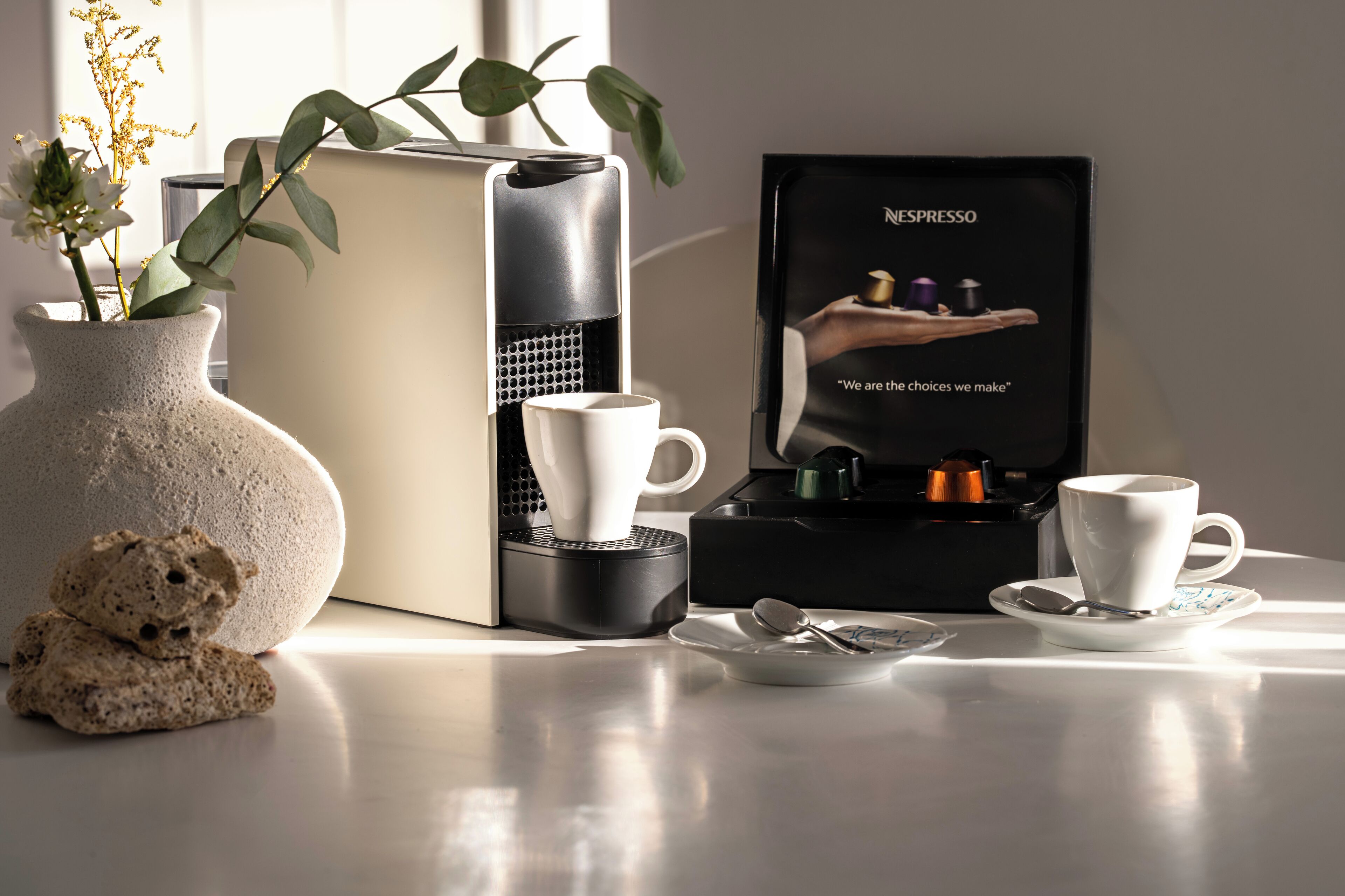 Een koffieapparaat, een vaas met bloemen, een teddybeer en een doos met een koffiekop.
