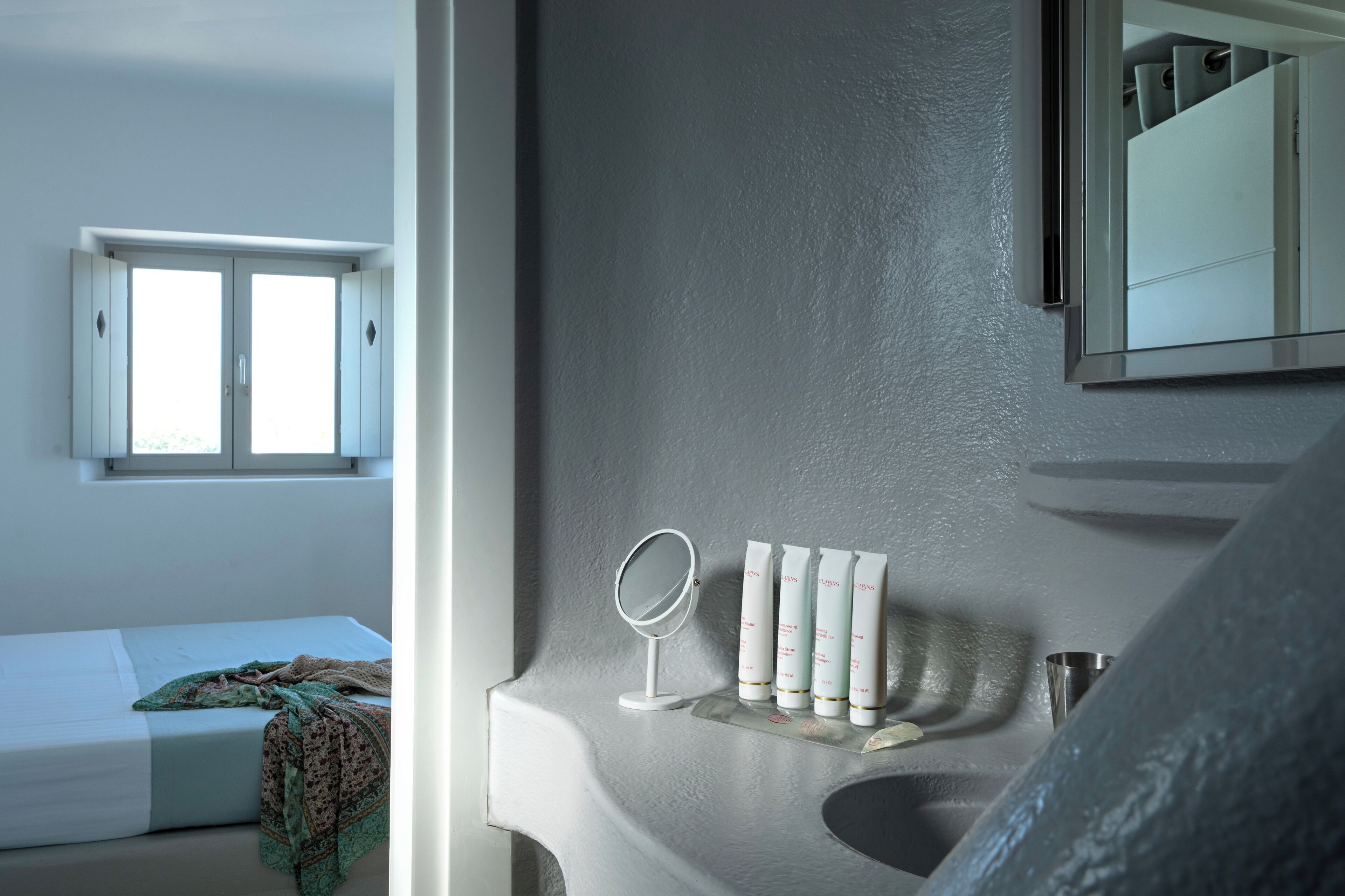 A bathroom with a mirror, a sink, and toiletries.