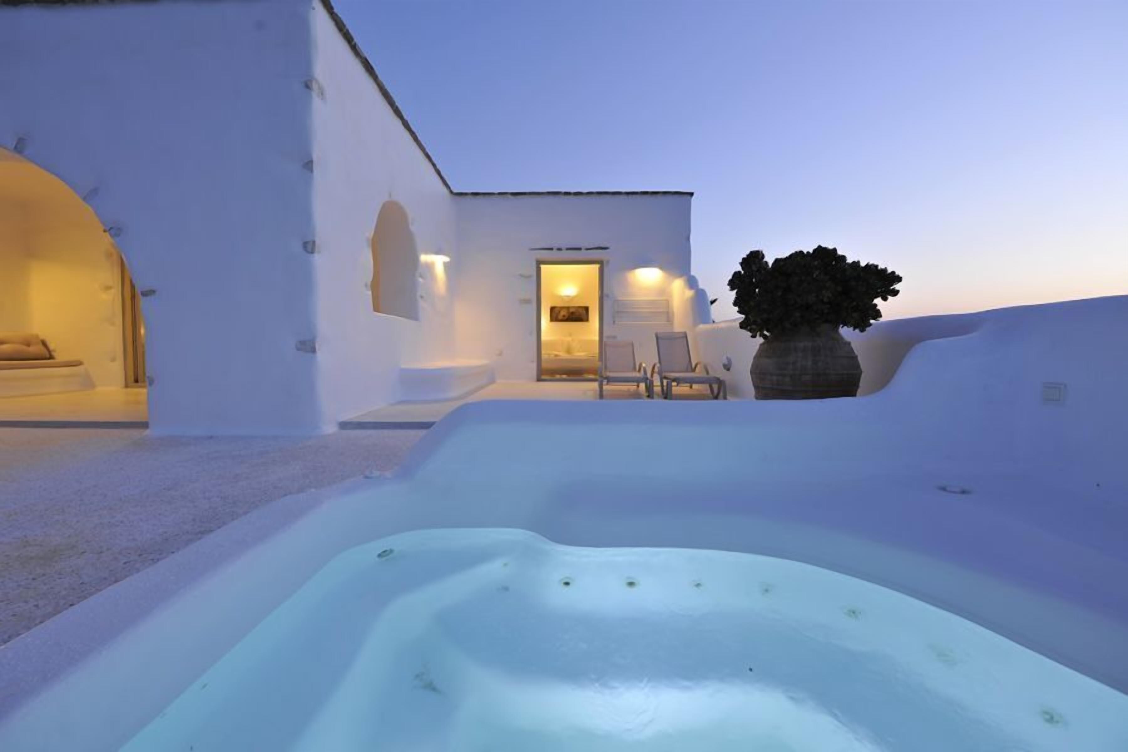 Un edificio moderno blanco con jacuzzi, mobiliario exterior y una planta en maceta.
