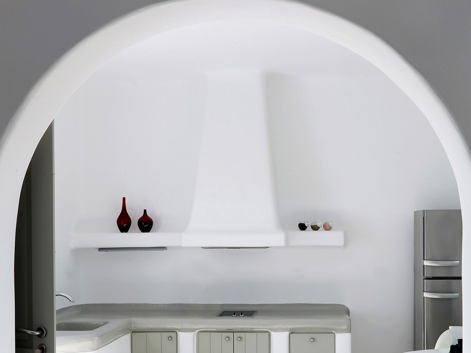 Una cocina moderna con un arco blanco, un refrigerador de acero inoxidable y una encimera con un lavamanos.