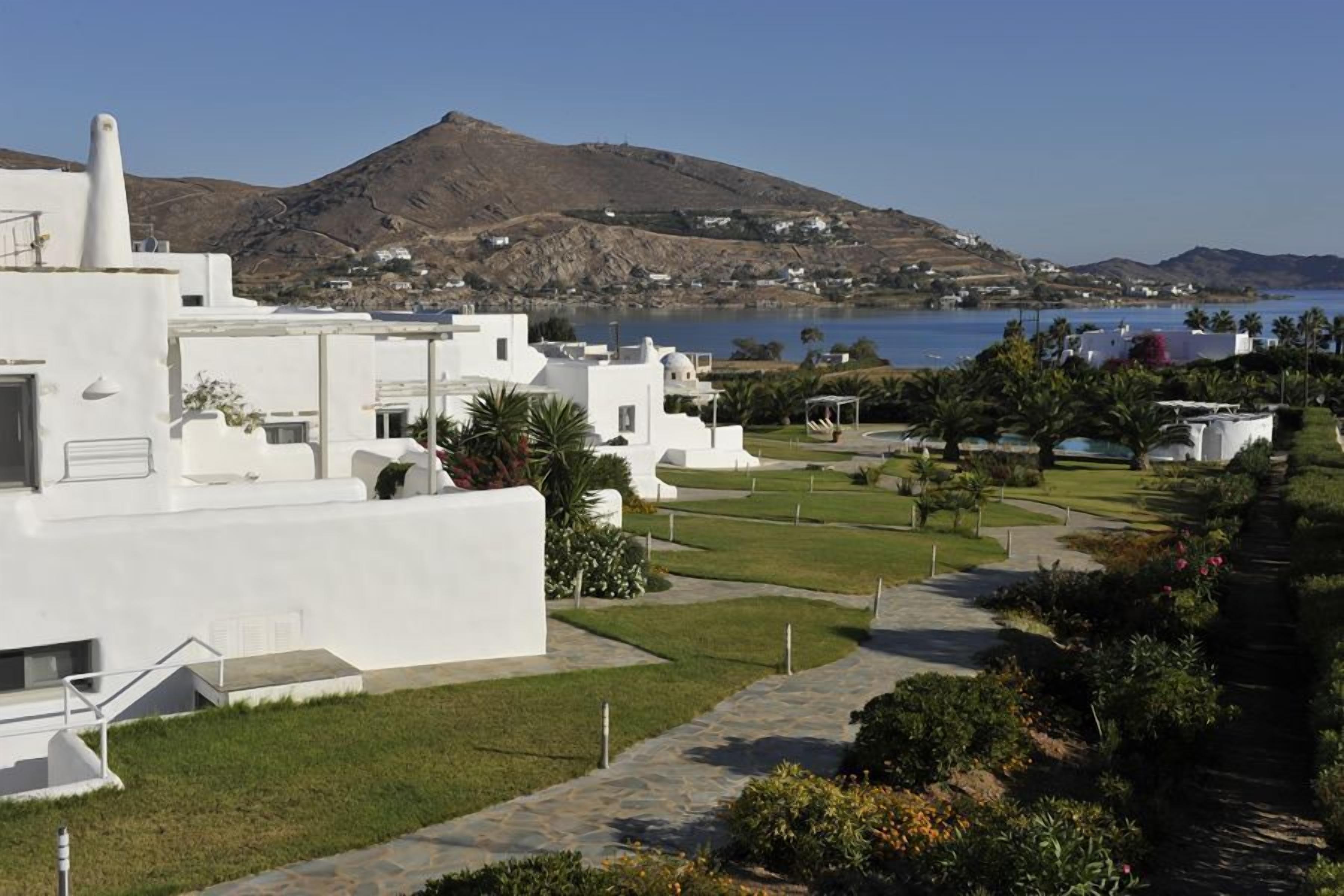 Una località balneare con edifici bianchi, una limpida vista sul mare e montagne sullo sfondo.