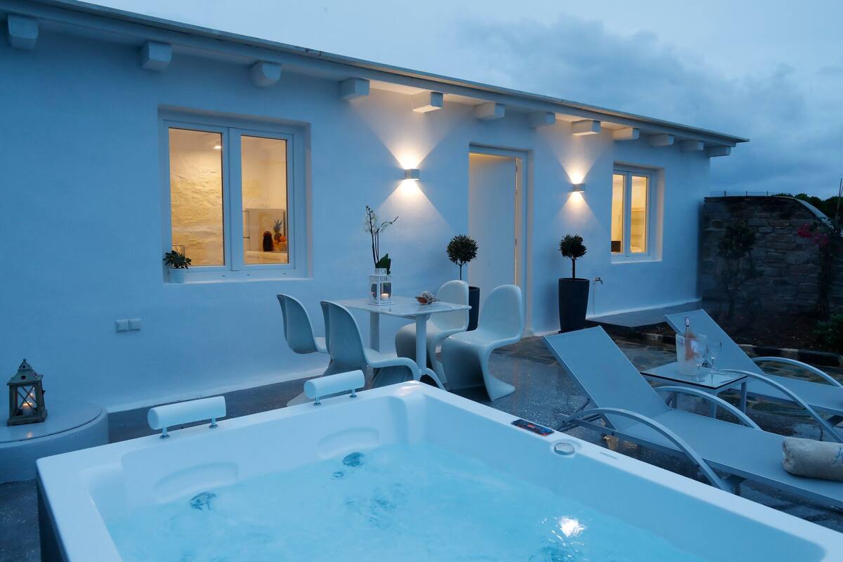 A modern house with a pool area, including a hot tub and lounge chairs.
