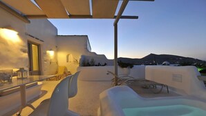 A modern outdoor seating area with a pool, white walls, and a view of the landscape. - Angels Villas (Paros)
