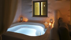 A modern bathroom with a large bathtub, a window with curtains, and two wall-mounted lights. - Angels Villas (Paros)