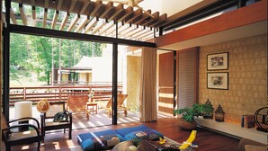 A modern living room with a large sliding glass door leading to an outdoor deck, a round coffee table, and a sofa. - Forest Village (Fujikawaguchiko)