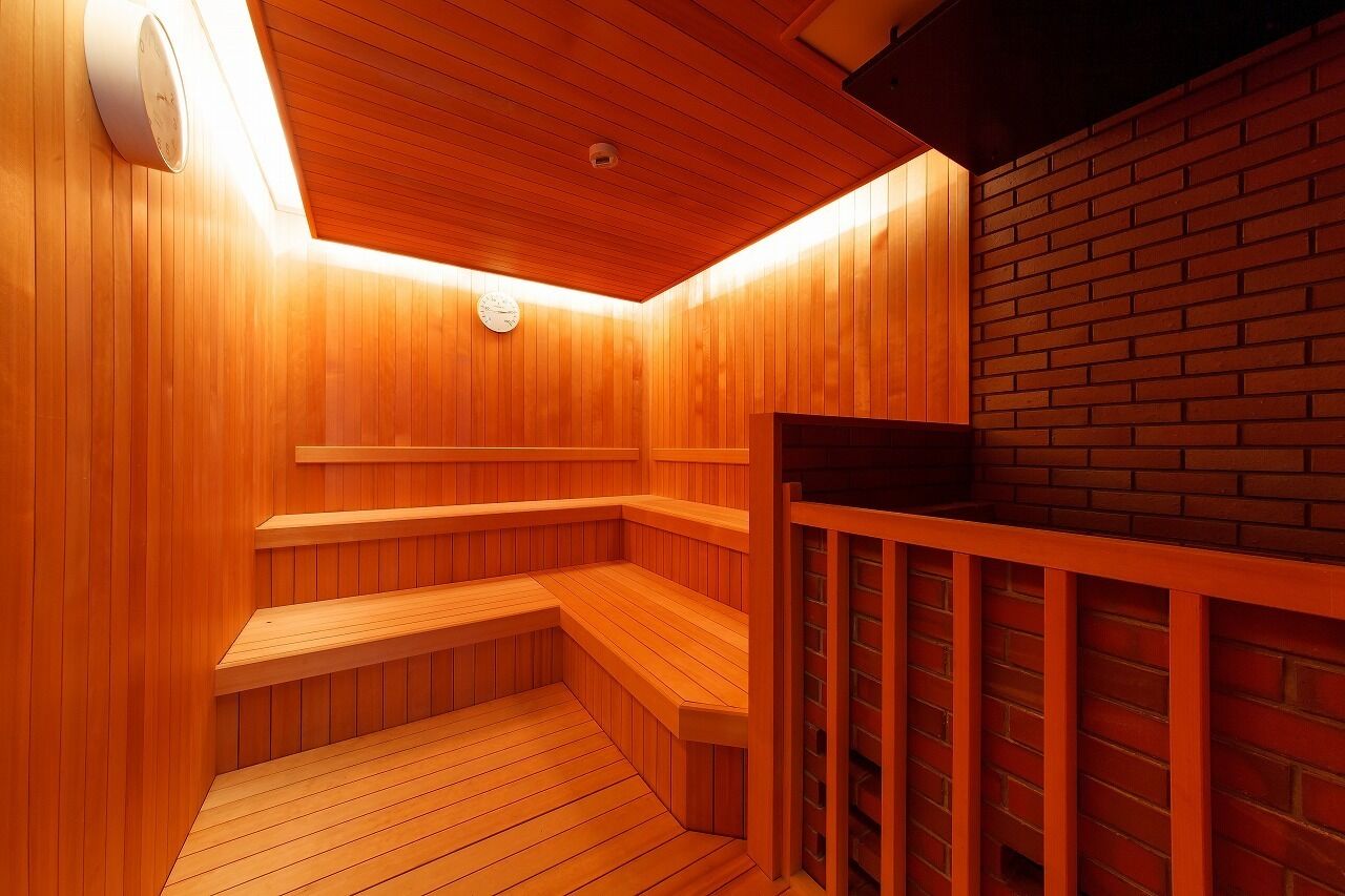 A wooden sauna with benches and a brick wall.