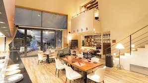 A spacious dining area with a high ceiling, a staircase, and a view of a Christmas tree outside. - Forest Village (Fujikawaguchiko)