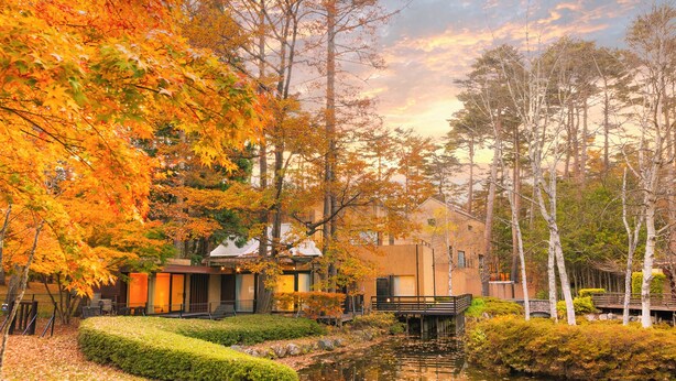 A modern building with a garden and a pond, surrounded by autumn trees. - Forest Village (Fujikawaguchiko)