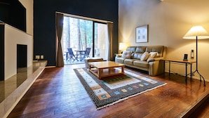 A modern living room with a wooden floor, a sofa, a coffee table, and a lamp. - Forest Village (Fujikawaguchiko)