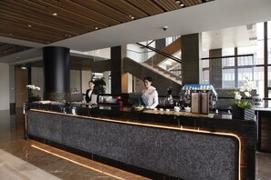 A modern hotel lobby with a reception desk, a staircase, and large windows. - Yanqi Hotel (Huairou)