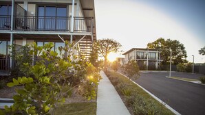 A modern building with a balcony, a clear sidewalk, and a street in the background. - Kings Park (Chinchilla)