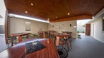 Un espace de restauration en plein air avec plusieurs tables et chaises en bois, un mur en pierre et un plafond en bois.