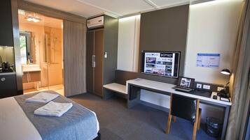 A hotel room with a bed, a desk, a computer, and a TV.