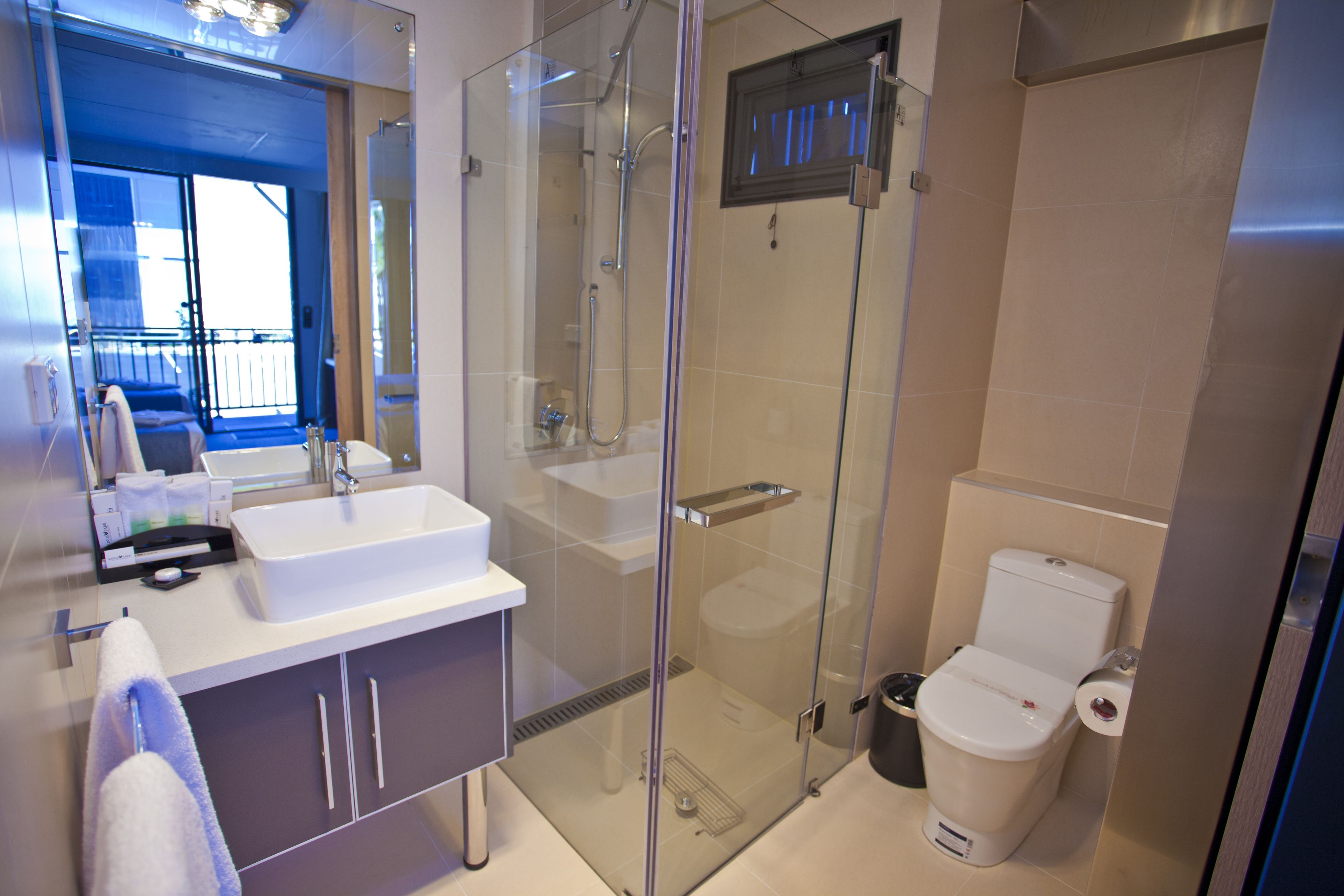 A modern bathroom with a glass-enclosed shower, a white sink, and a toilet.