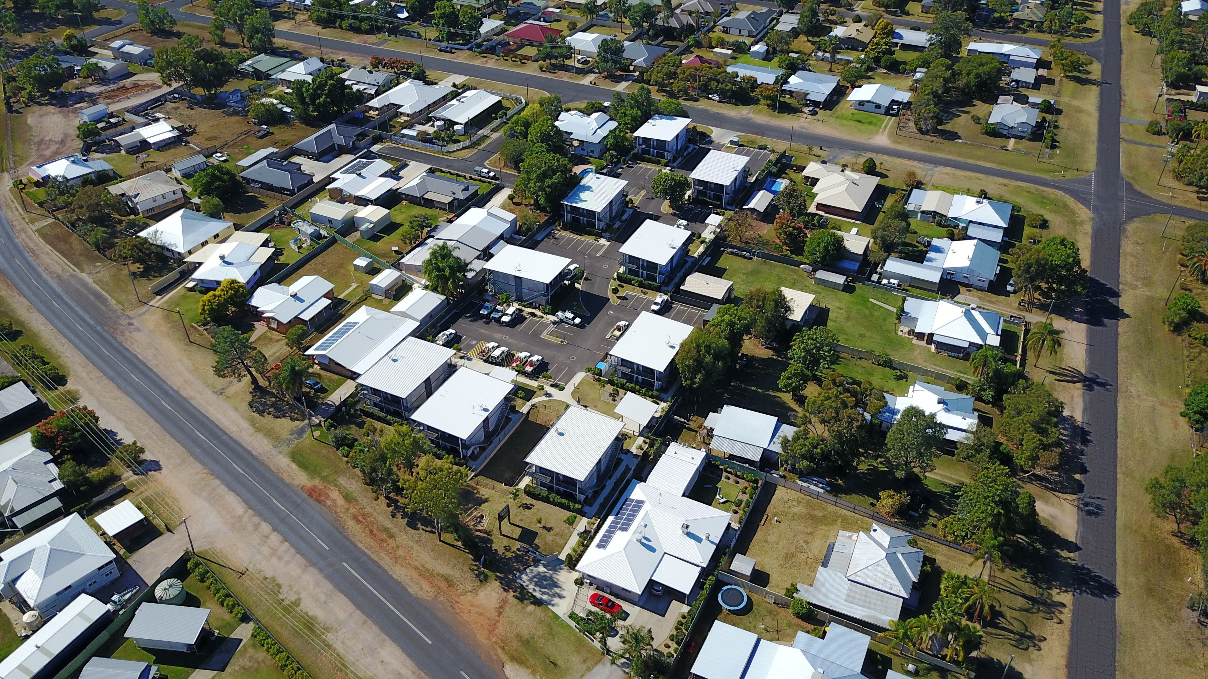 An aerial view of a residential area with multiple detached houses, roads, and greenery.