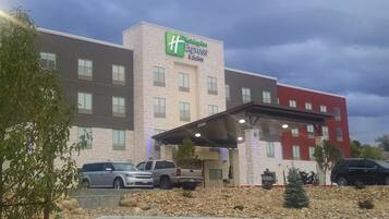 Edificio de Holiday Inn Express & Suites con un acceso cubierto y varios vehículos estacionados al frente.