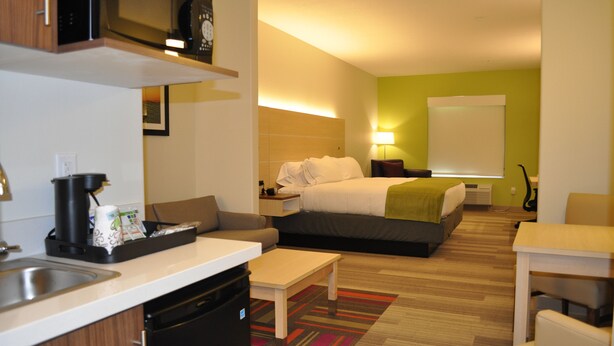 A hotel room with a kitchenette, a bed, a desk, and a dining area. - Holiday Inn Express & Suites Price by IHG (Price)
