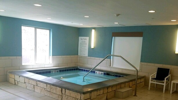 Une piscine bordée de pierres, une chaise et un panneau indiquant les règles du centre de bien-être.