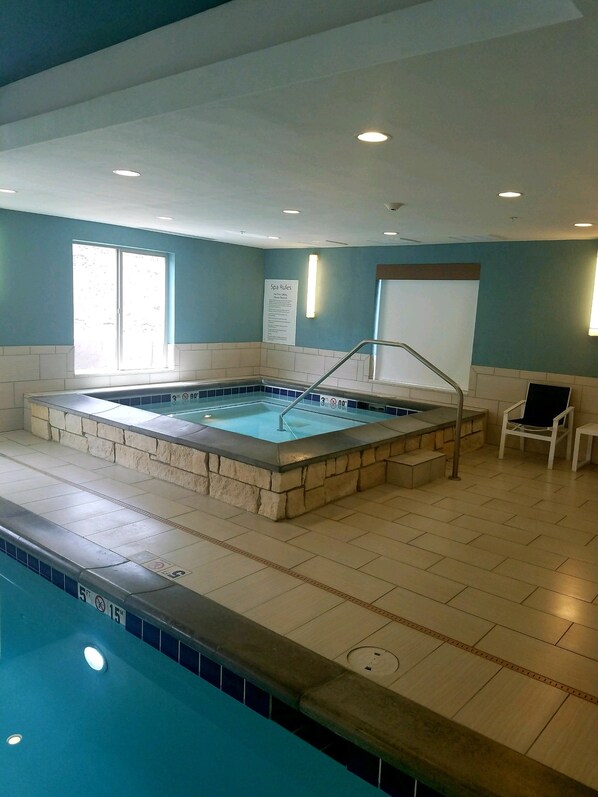 Une piscine bordée de pierres, une chaise et un panneau indiquant les règles du centre de bien-être.