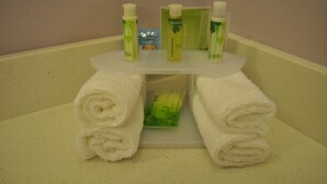 A bathroom with a white sink, two rolled white towels, and three green bottles of soap on the sink. - Holiday Inn Express & Suites Price by IHG (Price)