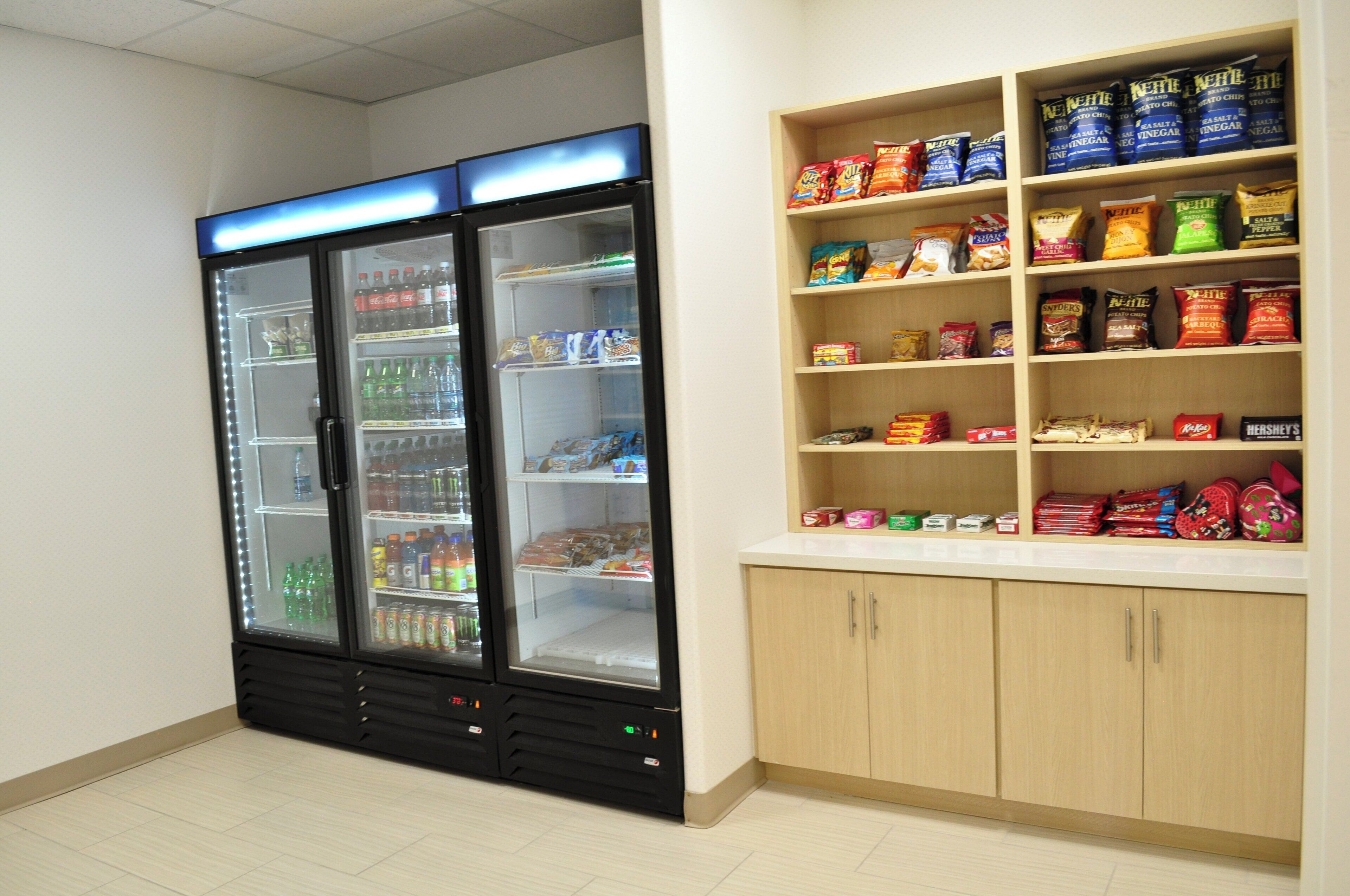A vending machine stocked with beverages and snacks, and a shelf with packaged food items.