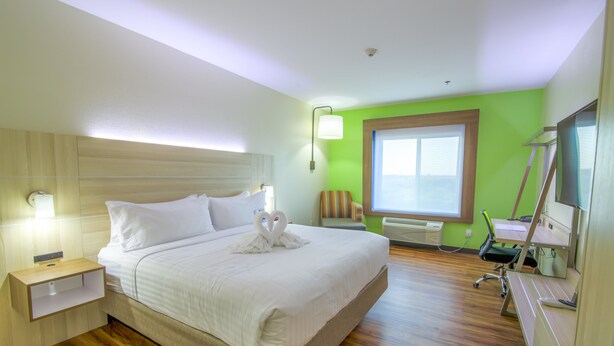 A hotel room with a large bed, a desk with a chair, a window, and a wall-mounted TV. - Holiday Inn Express & Suites Raymondville by IHG (Raymondville)