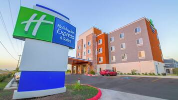 A Holiday Inn Express & Suites hotel with a prominent sign, a parking lot, and a red fire lane curb.