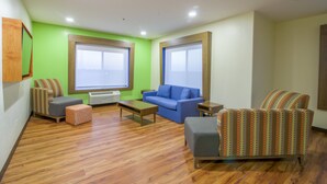 A modern living room with a blue sofa, a patterned armchair, and a wooden coffee table. - Holiday Inn Express & Suites Raymondville by IHG (Raymondville)