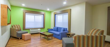 A modern living room with a blue sofa, a patterned armchair, and a wooden coffee table.