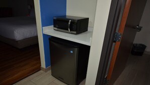 A compact kitchenette with a microwave on a shelf and a small refrigerator. - Holiday Inn Express & Suites Raymondville by IHG (Raymondville)