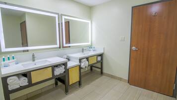Une salle de bain avec deux lavabos, un grand miroir et une porte en bois.