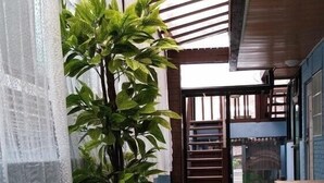 A narrow hallway with a green artificial turf floor, a potted plant, and a wooden bench. - Again Seoul Guesthouse (Seoul)