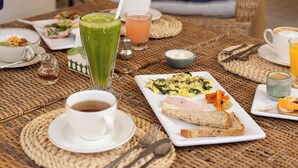 A breakfast table with various dishes, including toast, eggs, and a green smoothie, set on a woven mat. - Villa Vicuña Hotel Boutique (Salta)