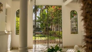 A courtyard with a white column, a metal gate, and a view of greenery. - Villa Vicuña Hotel Boutique (Salta)