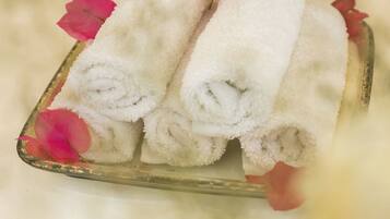 A glass tray with folded white towels and pink flower petals.
