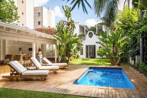 Un espace aménagé au bord de la piscine, avec des chaises longues, une petite piscine et une végétation luxuriante.