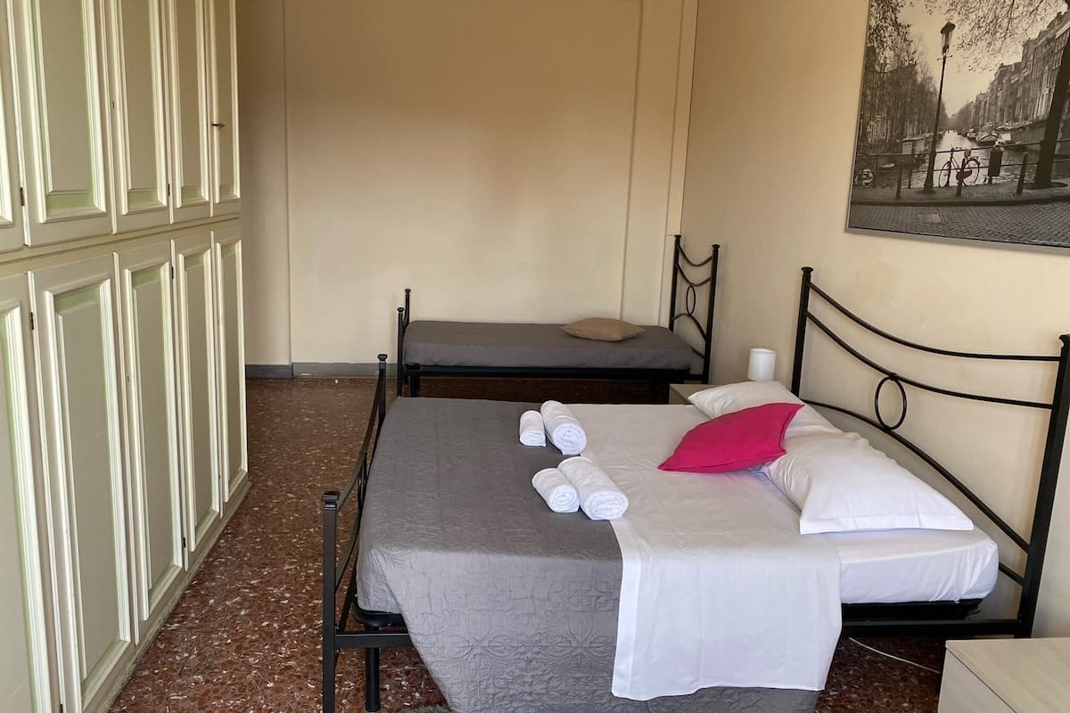 Un dormitorio con dos camas, suelo de mármol, un cuadro en la pared y un armario.