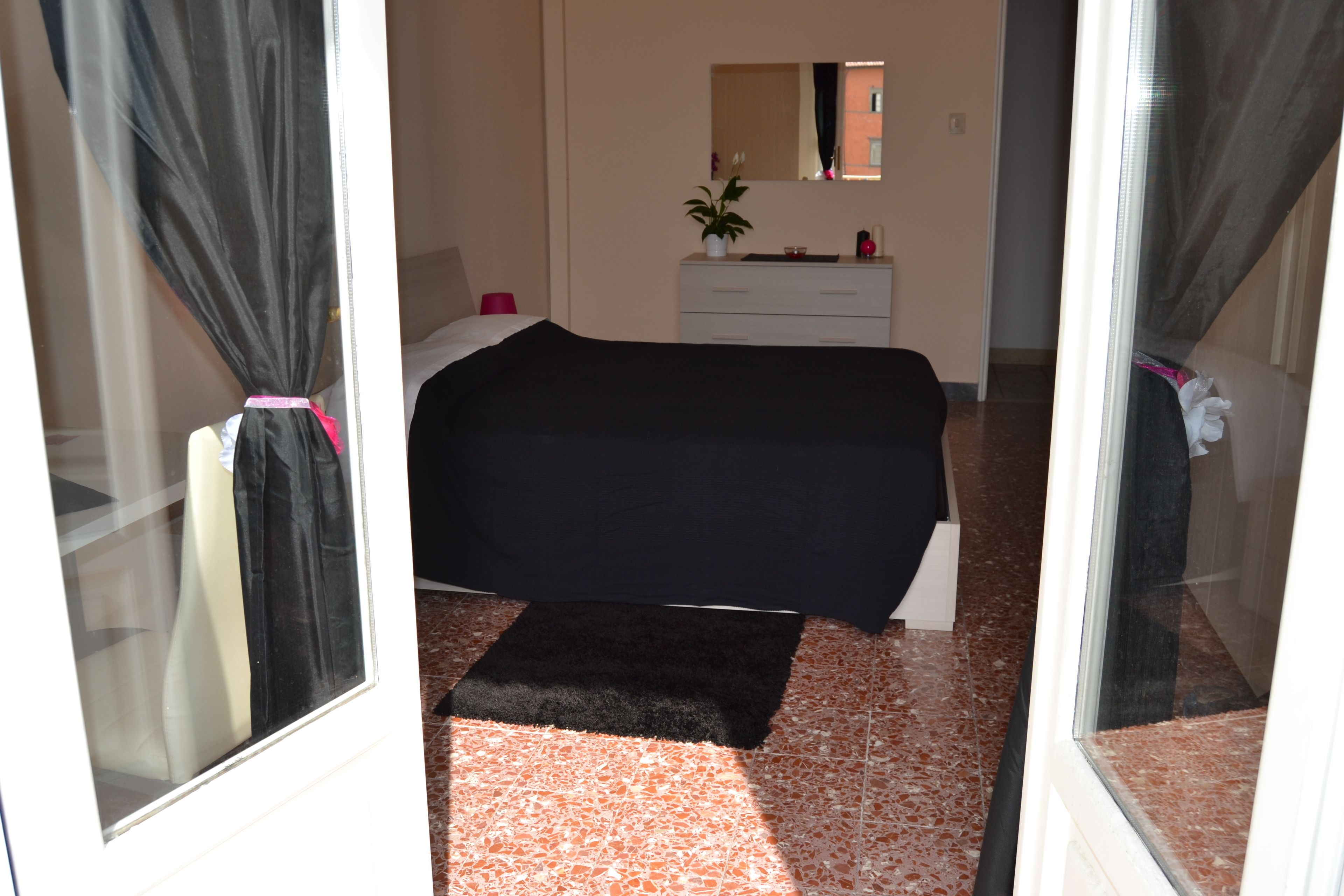 A bedroom with a bed, a dresser, a mirror, and a potted plant.