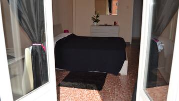 A bedroom with a bed, a dresser, a mirror, and a potted plant.
