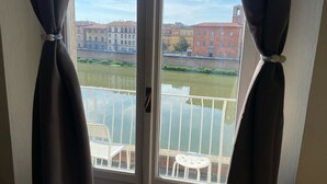 A balcony with a view of a river and buildings. - You & Me (Pisa)