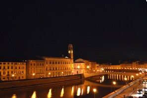 A nighttime cityscape with illuminated buildings and a river reflecting lights.