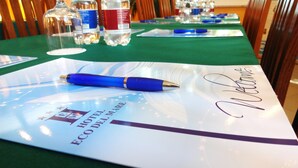 A hotel brochure on a table with a blue pen, a welcome sign, and water bottles. - Hotel Eco del Mare (Massa)
